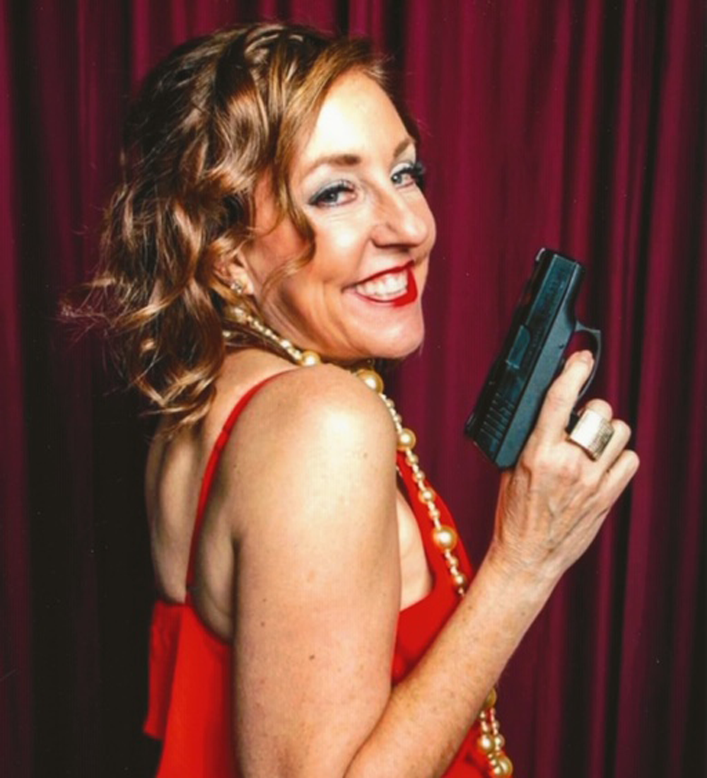 Photo of caucasion blonde woman in red dress with gun