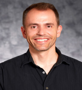 Photo of a caucasion male with short dark hair wearing a black shirt